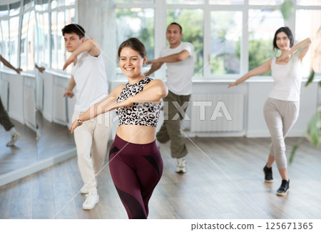 Smiling girl enjoying vigorous dance at group class Smiling girl enjoying vigorous dance at group class 125671365
