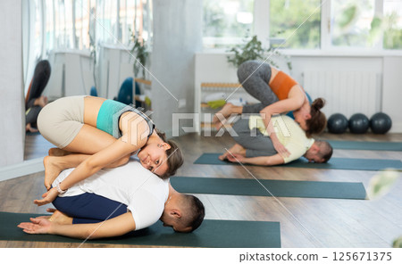 Young couple practicing acro yoga on mat in studio together, flexibility class workout 125671375