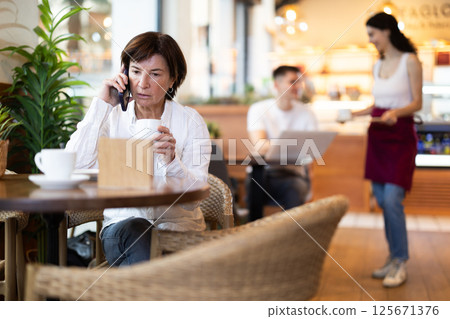 Elderly woman talking on phone in cafe 125671376