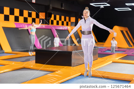 Portrait of sporty fit woman enjoying weekend while spending time on trampolines in game club indoors 125671464