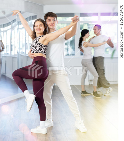 Happy young woman enjoying training dancing active swing with male partner in dance room. Social dancing concept 125671470