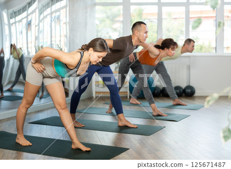 Lovers of active lifestyle on yoga mat perform doing Ardha Uttanasana in gym 125671487