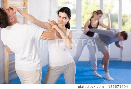 Young girl practicing self-defense techniques in pairs with guy 125671494