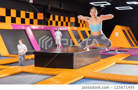 Young woman trains jumping in trampoline center 125671495