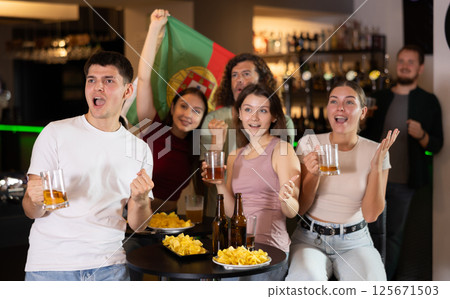 Friends watches a match of their favorite Portugal team on TV, drinks beer and shouts chants 125671503