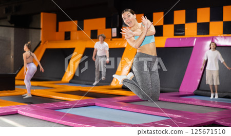 Young woman trains jumping in trampoline center Young woman trains jumping in trampoline center 125671510