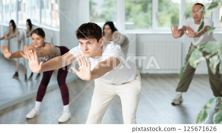Hispanic guy performing stretching exercises before dance class Hispanic guy performing stretching exercises before dance class 125671626