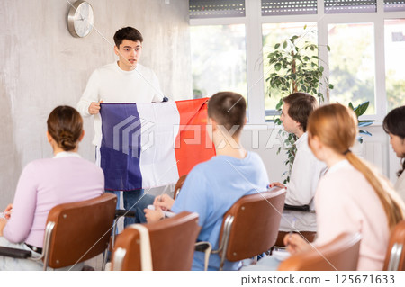 Young teacher holding flag of France in front of group of students 125671633