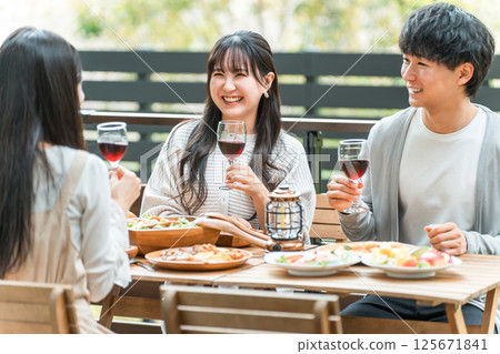 Group of young Asian men and women having a home party glamping on a wooden deck 125671841