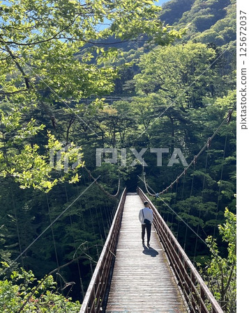 man crossing suspension bridge 125672037