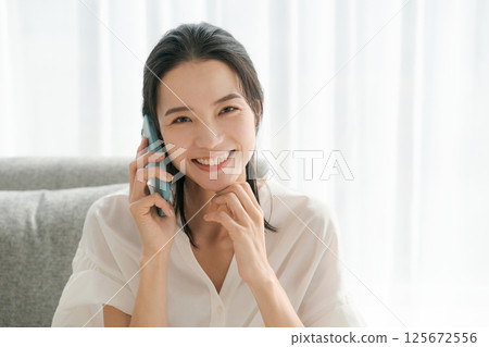 A woman in her 30s talking on a smartphone 125672556
