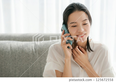 A woman in her 30s talking on a smartphone 125672558
