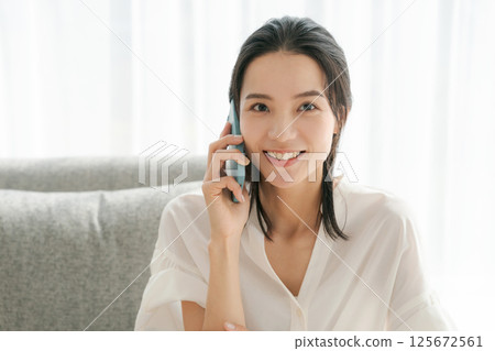 A woman in her 30s talking on a smartphone 125672561