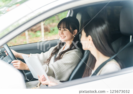 A woman driving a car and her female friend in the passenger seat (driver, drive) 125673032