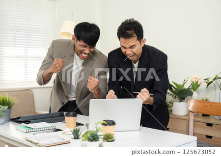 Celebration and Teamwork. Two men expressing joy and excitement in a modern office setting. 125673052