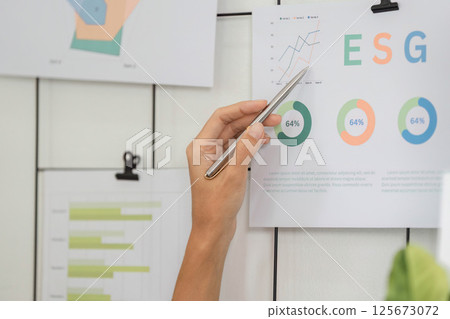 ESG analysis featuring hand pointing at sustainable metrics on wall 125673072