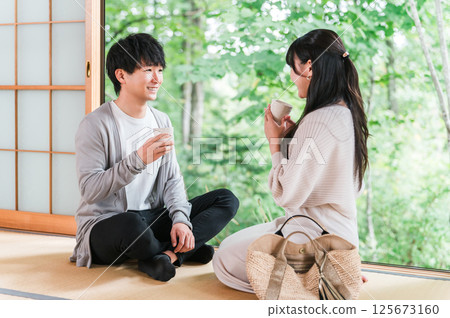 A couple staying at a hot spring inn and Japanese-style room on a domestic trip and looking at the garden view 125673160