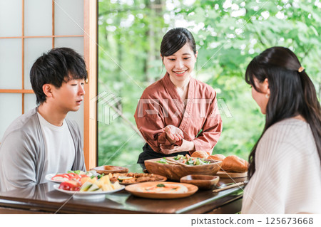 A female inn staff member explaining the dishes in a guest room at a hot spring inn A female inn staff member explaining the dishes in a guest room at a hot spring inn 125673668