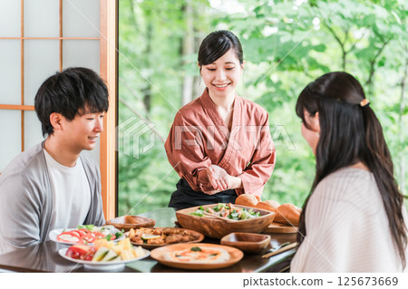 A female inn staff member explaining the dishes in a guest room at a hot spring inn A female inn staff member explaining the dishes in a guest room at a hot spring inn 125673669