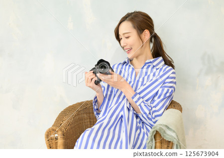 Woman holding a single-lens camera Woman holding a single-lens camera 125673904