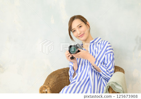 Woman holding a single-lens camera Woman holding a single-lens camera 125673908