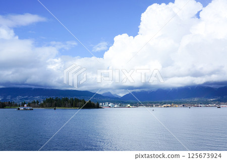A view of the town and sea on the opposite shore from Vancouver under blue skies and cumulonimbus clouds 125673924