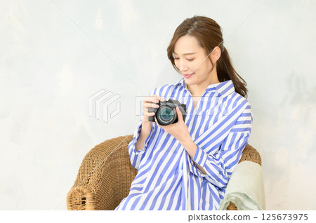 Woman holding a single-lens camera Woman holding a single-lens camera 125673975