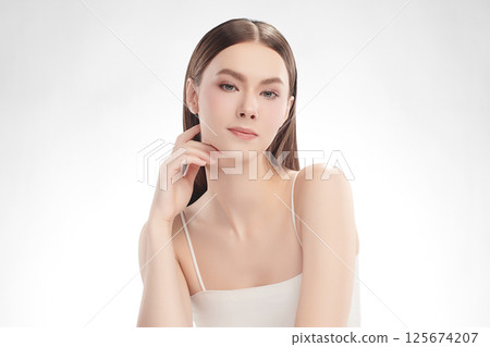 A beautiful young woman with clean, fresh skin against a white background. Skincare, facial treatment, cosmetology, beauty, and spa. An elegant portrait of an woman. 125674207