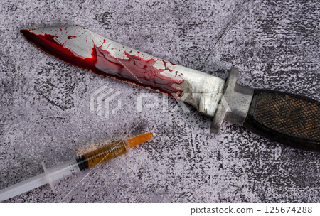 A combat knife in blood lies next to a syringe on a marble background. High quality photo 125674288