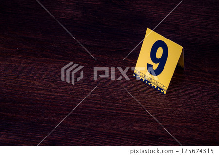 Yellow crime scene evidence marker number 9 on the floor in the room. High quality photo Yellow crime scene evidence marker number 9 on the floor in the room. High quality photo 125674315