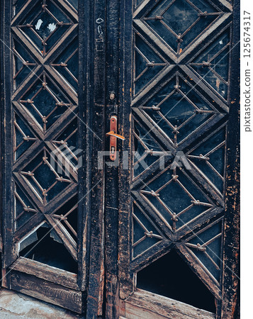 Double antique wooden doors with partially knocked out glass inserts. High quality photo Double antique wooden doors with partially knocked out glass inserts. High quality photo 125674317