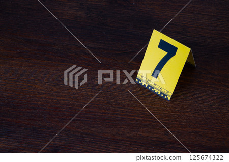 Yellow crime scene evidence marker number 7 on the floor in the room. High quality photo 125674322