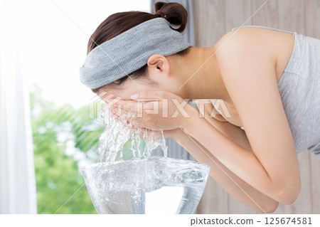 年輕的亞洲女子正在洗臉。 年輕的亞洲女子正在洗臉。 125674581