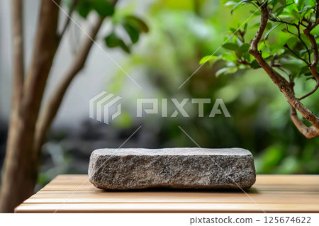 A geometric stone podium rests in a tranquil zen garden, offering a serene display for products 125674622