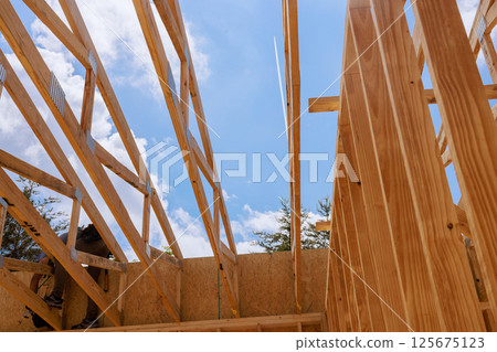 Workers are constructing wooden frame trusses structure on works day 125675123