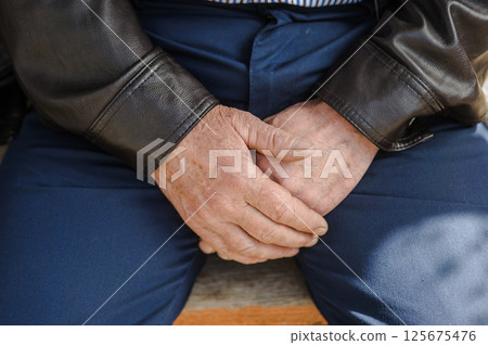 The man's aged hands, firmly folded. The man's trembling fingers. The man's aged hands, firmly folded. The man's trembling fingers. 125675476