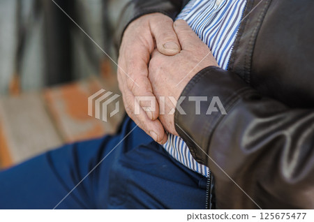 The old man's wrinkled hands are intertwined. The old man's shabby fingers, marked by time. The old man's wrinkled hands are intertwined. The old man's shabby fingers, marked by time. 125675477