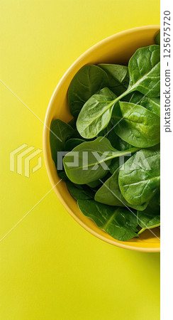 Fresh green spinach leaves in a yellow bowl on a vibrant yellow background, AI Generative 125675720