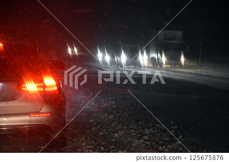 Driving on a snowy road at night Driving on a snowy road at night 125675876