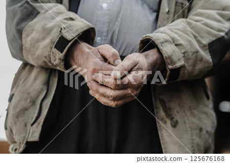 These hands have worked the land for decades. His old hands hold the weight of experience. 125676168