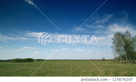 A Serene Countryside Landscape Under a Bright and Clear Sky Filled with White Clouds 125676297