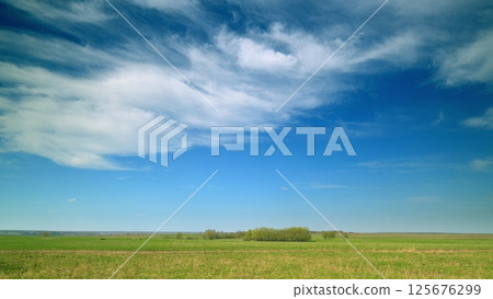 The Beautiful and Serene Countryside Featuring a Bright Blue Sky with Fluffy White Clouds 125676299