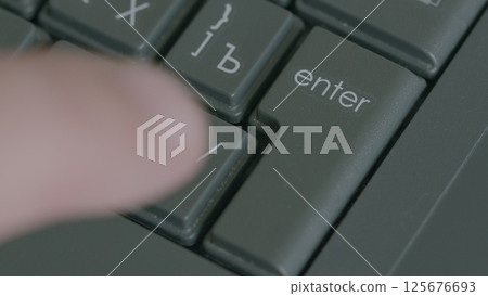 CloseUp View of a Hand Actively Pressing the Enter Key on a Computer Keyboard Device 125676693