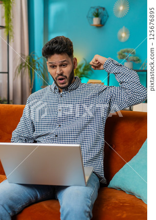 Amazed Indian man use laptop computer, receive good news message shocked by victory, celebrate win Amazed Indian man use laptop computer, receive good news message shocked by victory, celebrate win 125676895