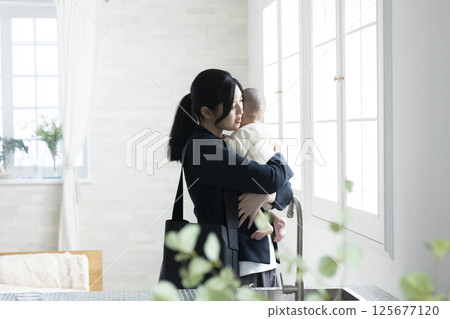 Working mother holding a baby Working mother holding a baby 125677120