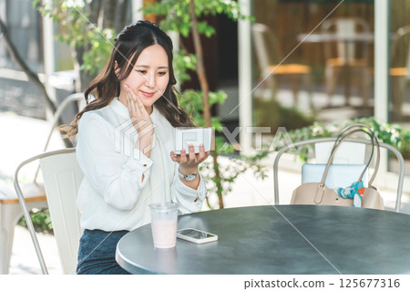 年輕女子補妝、化妝、在咖啡館照鏡子(保濕、防紫外線、防紫外線) 年輕女子補妝、化妝、在咖啡館照鏡子(保濕、防紫外線、防紫外線) 125677316