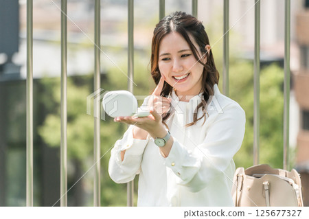 A woman touching up her makeup during a break (firmness, elasticity, beautiful skin, gloss, sagging, moisture, moisture) 125677327