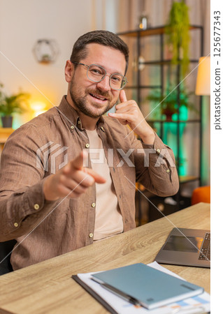 Young Caucasian businessman using laptop asking to make telephone conversation, gesturing call me Young Caucasian businessman using laptop asking to make telephone conversation, gesturing call me 125677343