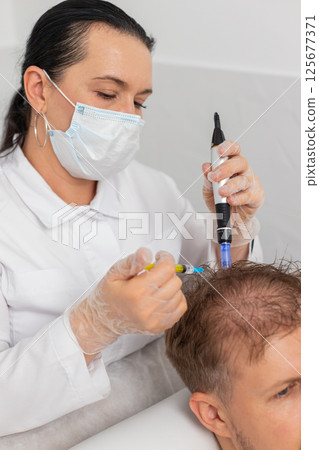 Trichologist doing man improve hair growth procedure, dermapen microneedling, vitamin injections Trichologist doing man improve hair growth procedure, dermapen microneedling, vitamin injections 125677371