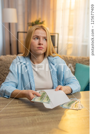 Young woman sorts money cash separating portions planning financial obligations, future expenses 125677409